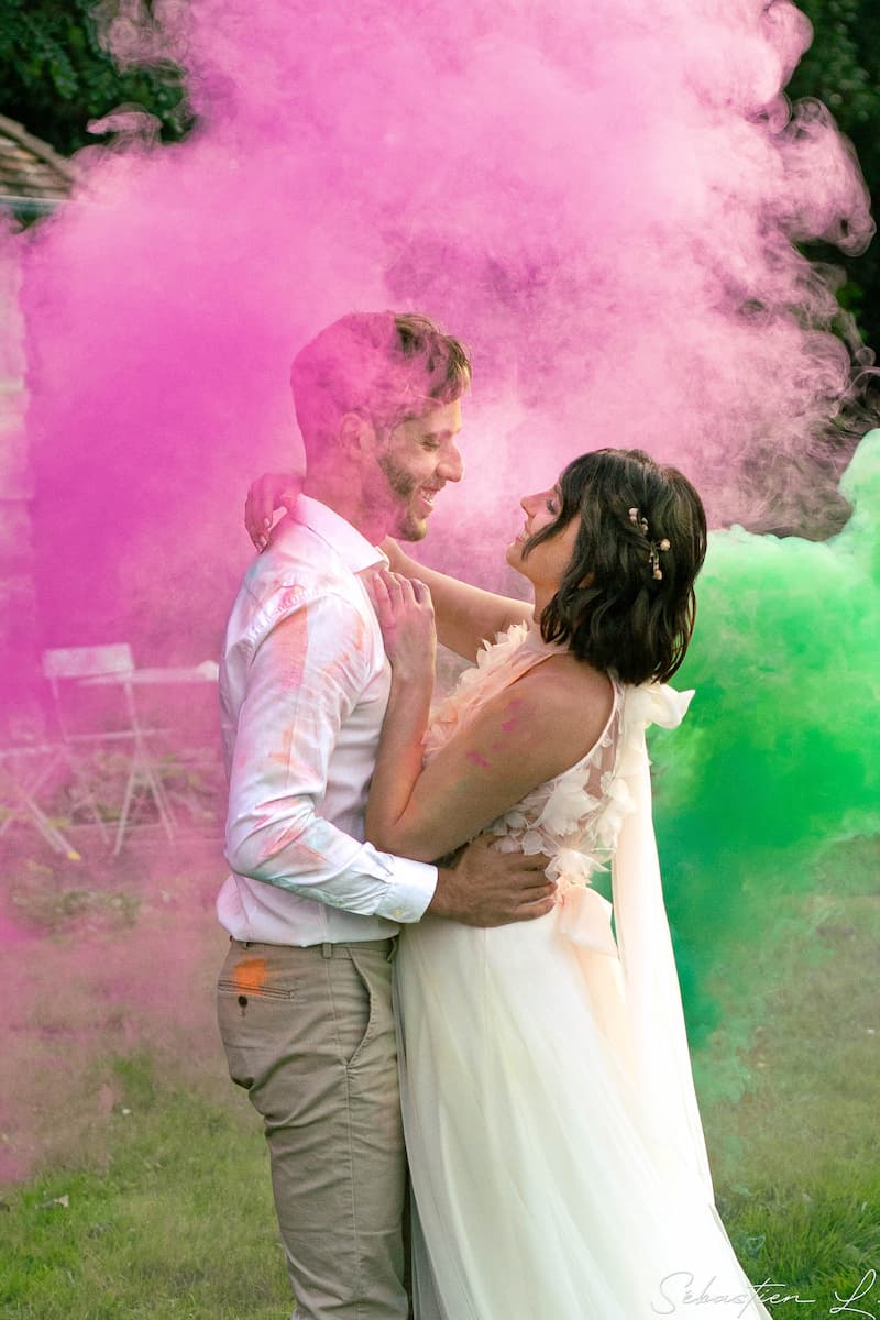 Mariés qui s'enlacent au milieu des fumigènes colorés Mariés qui s'enlacent au milieu des fumigènes colorés